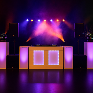 Verlichte DJ-opstelling met zuilen, speakers en kleurrijke podiumverlichting tegen zwarte achtergrond.