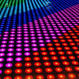 LED-dansvloer met patronen in groen, blauw, paars en rood tegen donkere achtergrond